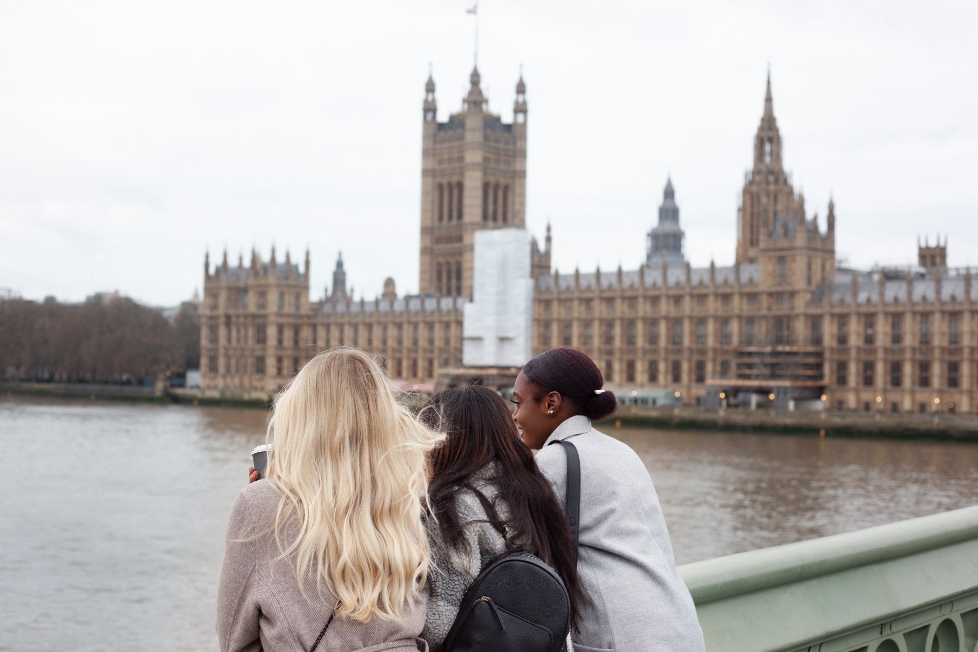 Tři mladé ženy u Temže v Londýně, v pozadí Westminsterský palác